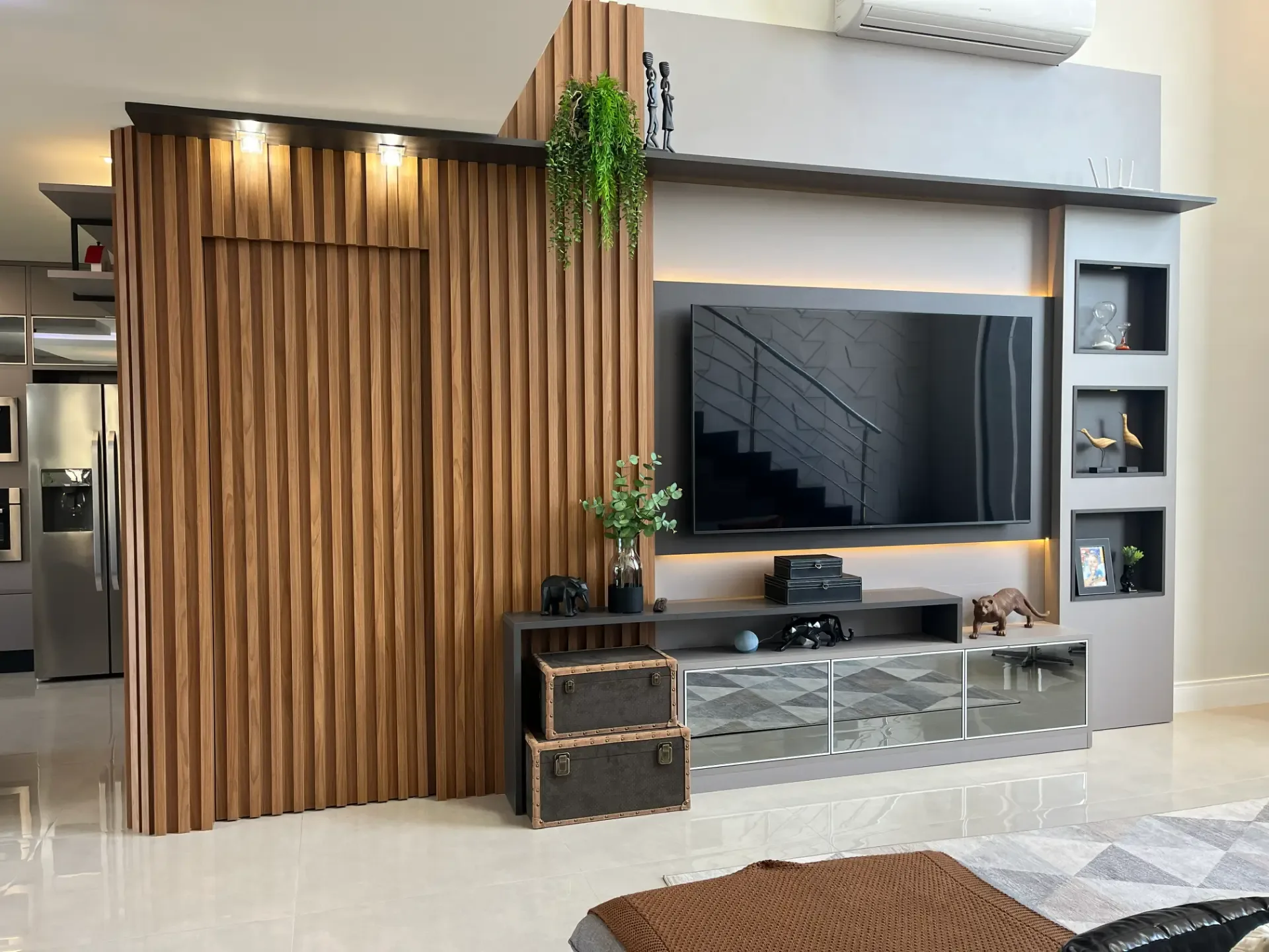 Living planejado com painel ripado amadeirado, rack sob medida e nichos iluminados