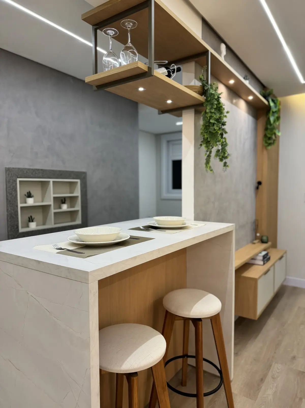 Espaço gourmet planejado com bancada, banquetas e nichos suspensos iluminados