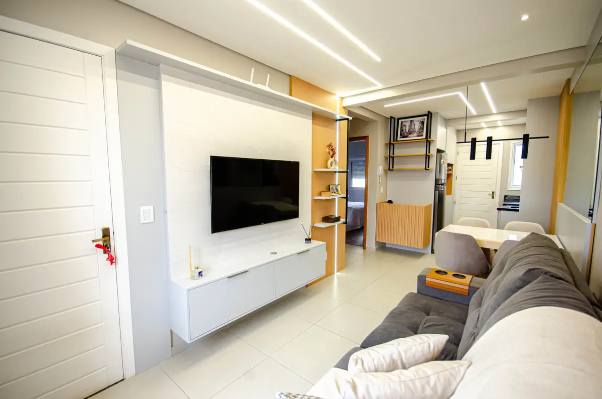 Living integrado com painel de TV planejado e iluminação linear no teto