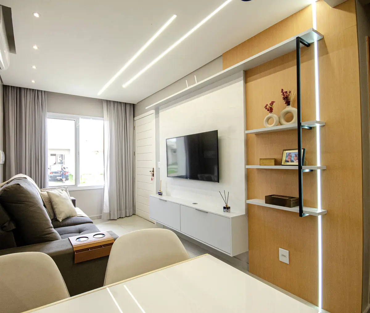 Sala de estar com painel de TV planejado, estante e revestimento amadeirado